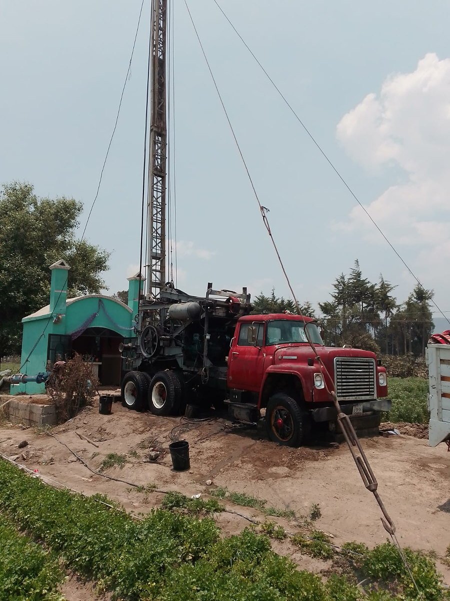 Camión perforador con torre levantada en parcela
