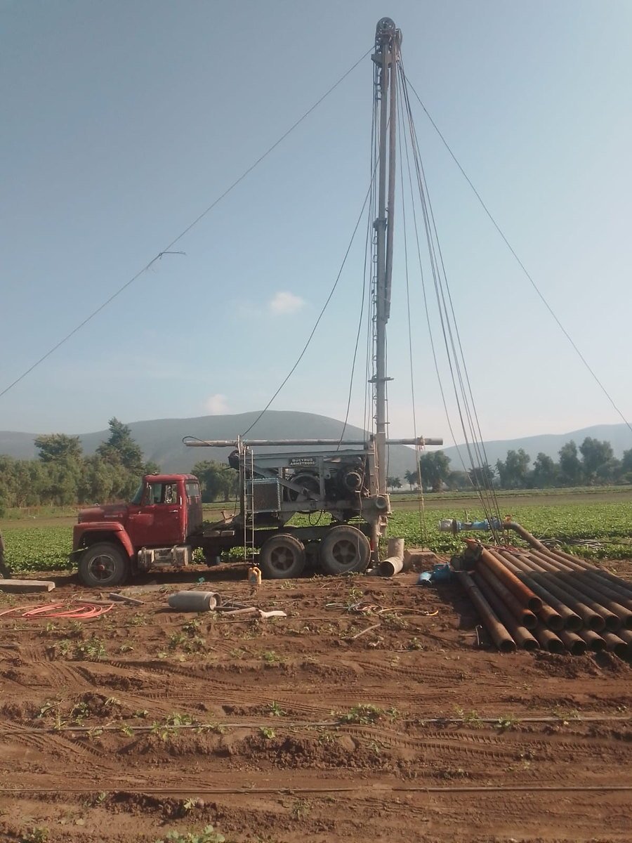Torre de perforación y camión rojo en el sitio de trabajo
